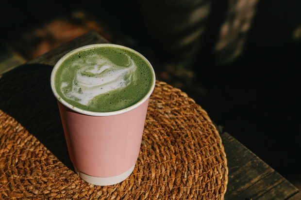 Matcha Latte in Pink Cup on Woven Placemat Outdoors