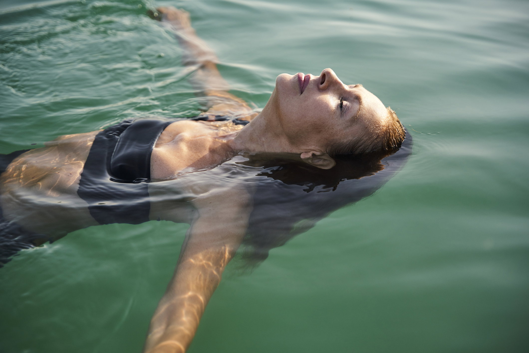 Mature woman floating in a lake with closed eyes