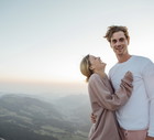 Switzerland, Grosser Mythen, portrait of happy young couple standing in mountainscape at sunrise