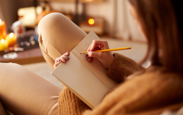 woman writing to diary at home on halloween