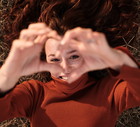 Woman gesturing the shape of a heart with hands outdoors