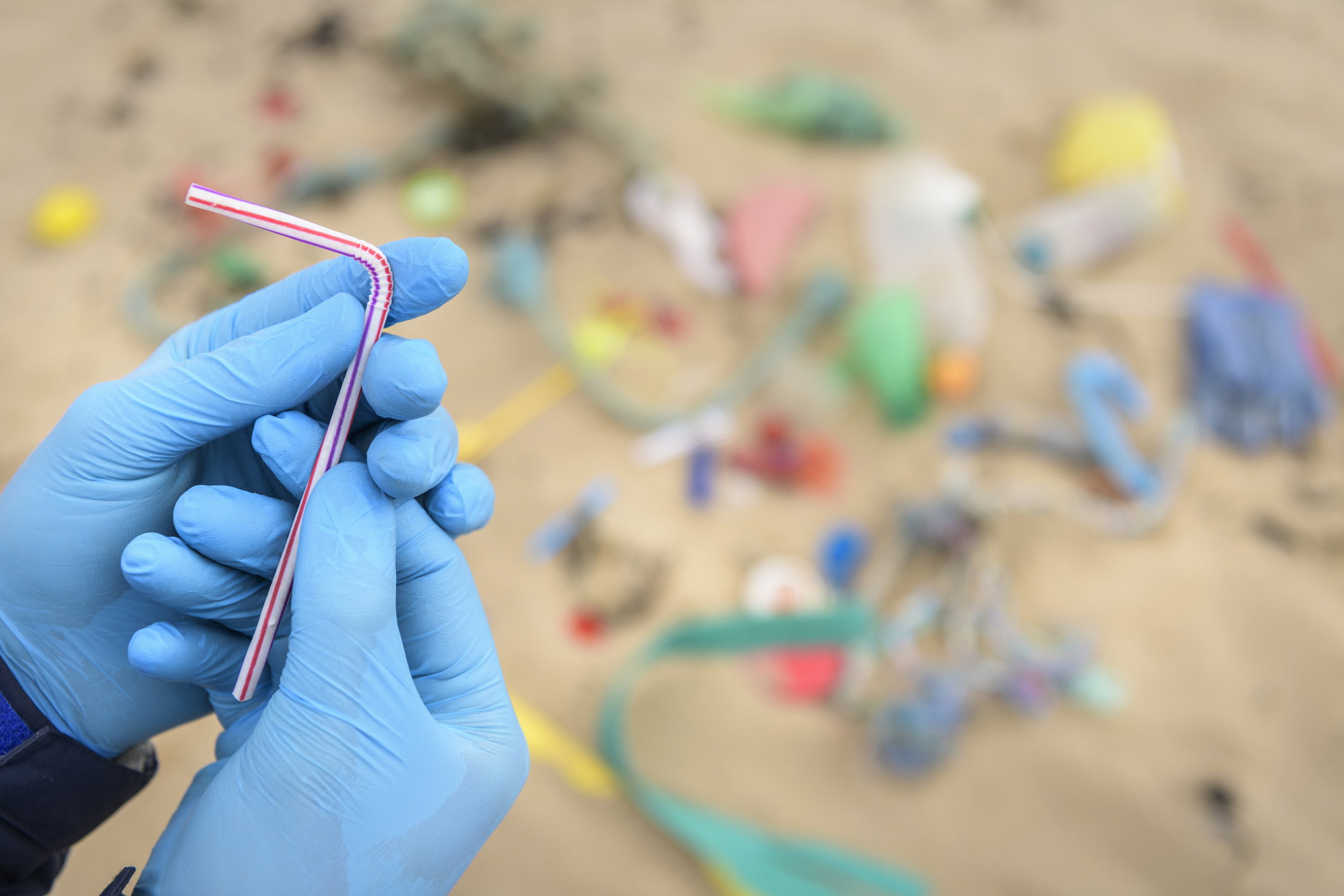 Man holding drinking straw from plastic pollution collected on beach, North East England, UK