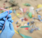 Man holding drinking straw from plastic pollution collected on beach, North East England, UK
