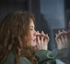 woman looking out of window into her reflection