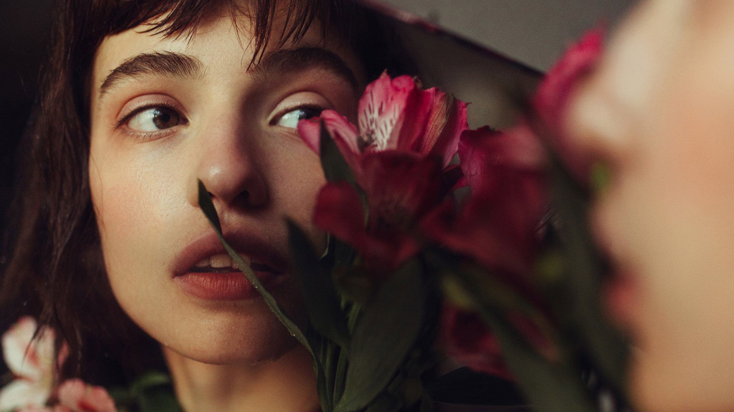 Young woman reflected in mirror with flowers