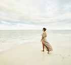 Wide shot of woman walking on beach and enjoying sunset at tropical resort