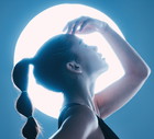Beauty, light and profile of a model in a studio with a sensual, soft and attractive pose. Cosmetic, magical and slim woman with a mystical glow posing by a moon while isolated by a blue background.