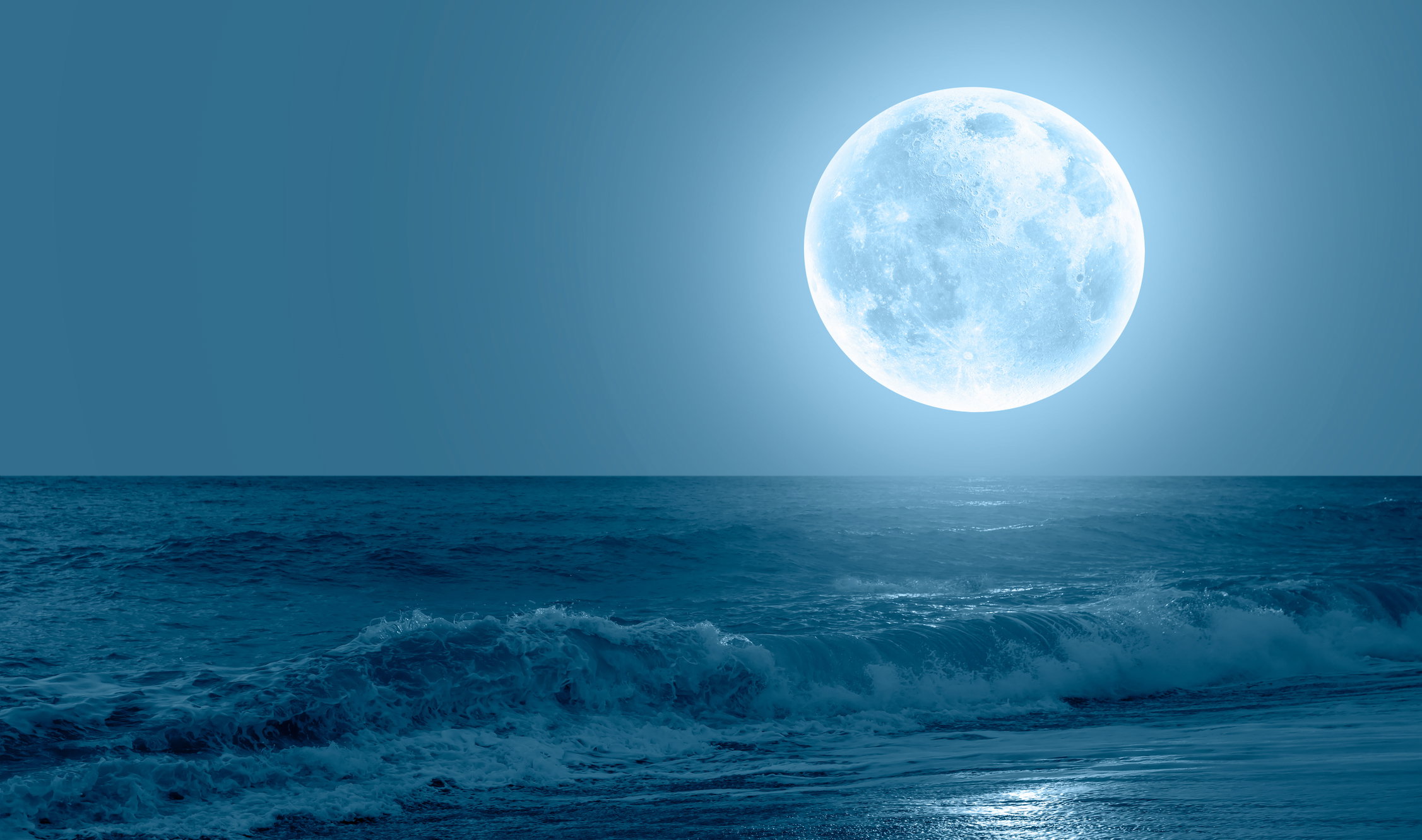 Night sky with blue moon in the clouds sea wave in the foreground