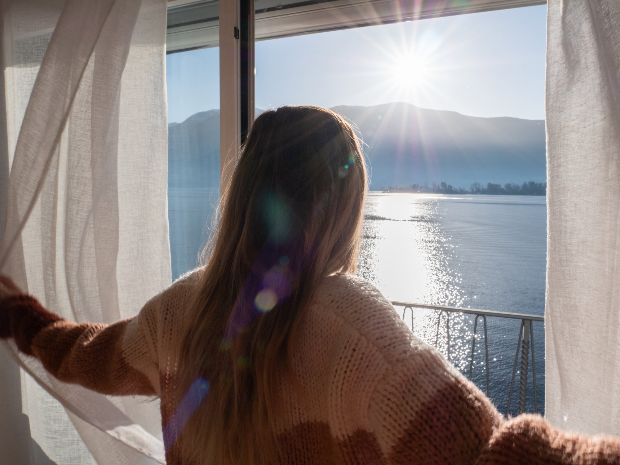 Female opens curtains at sunrise, new beginning new day