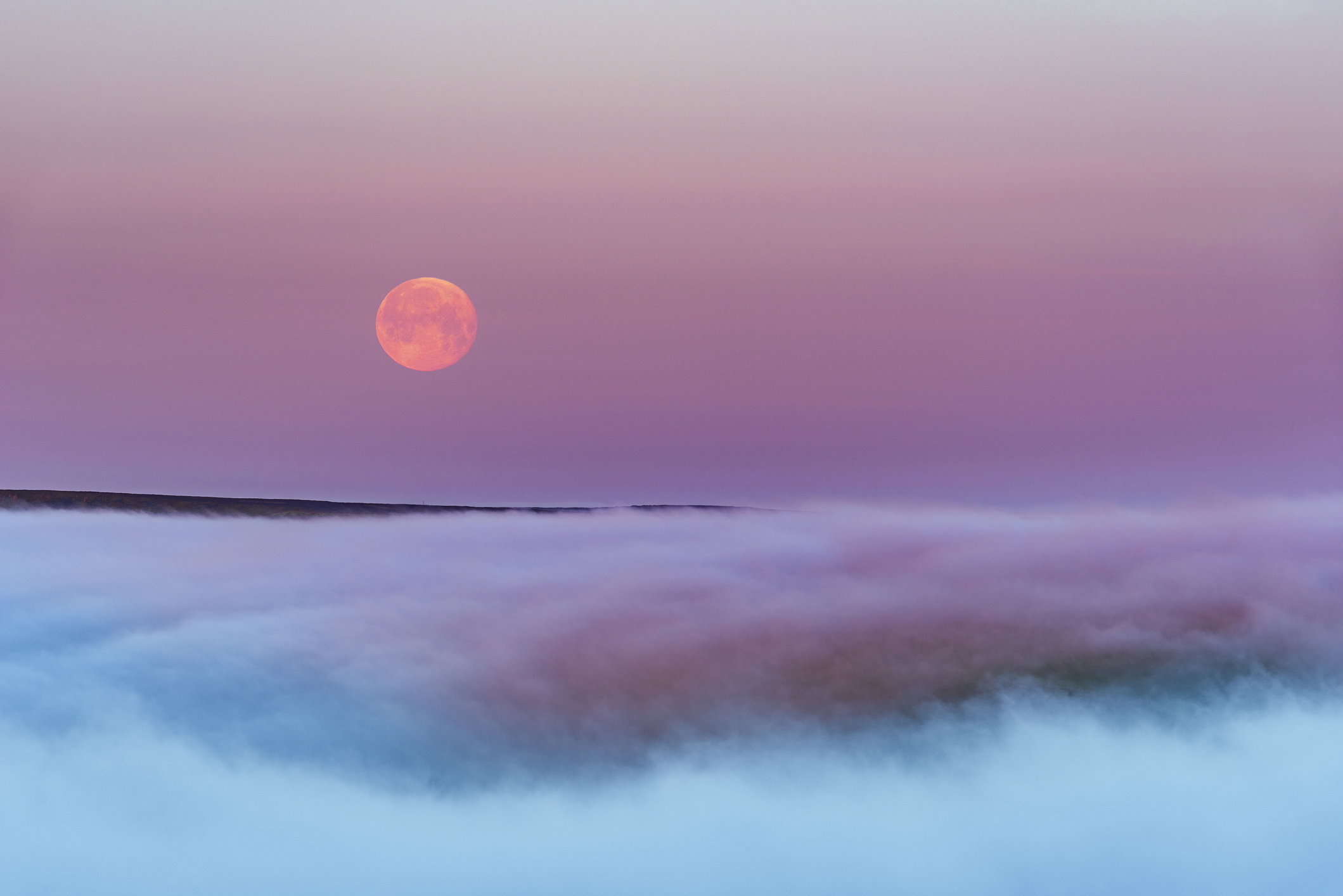 Super Flower Blood Moon over morning fog, Peak District National park.