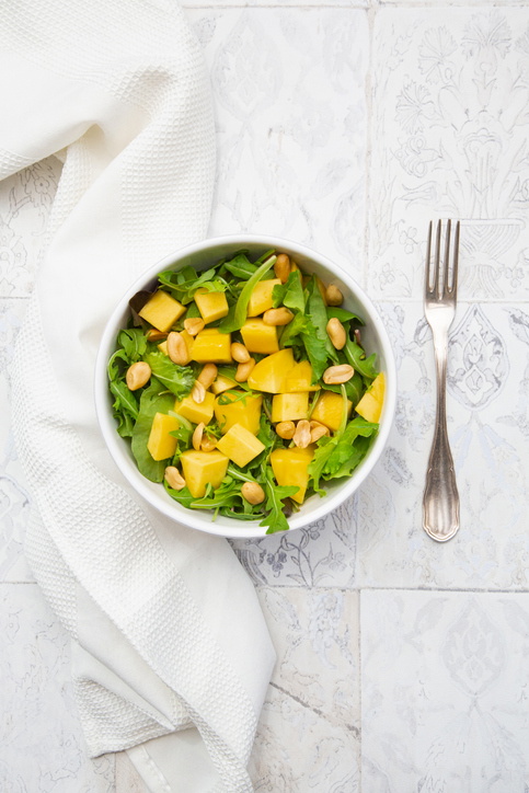 Directly above view of fresh salad in bowl amidst napkin and fork on tiled floor