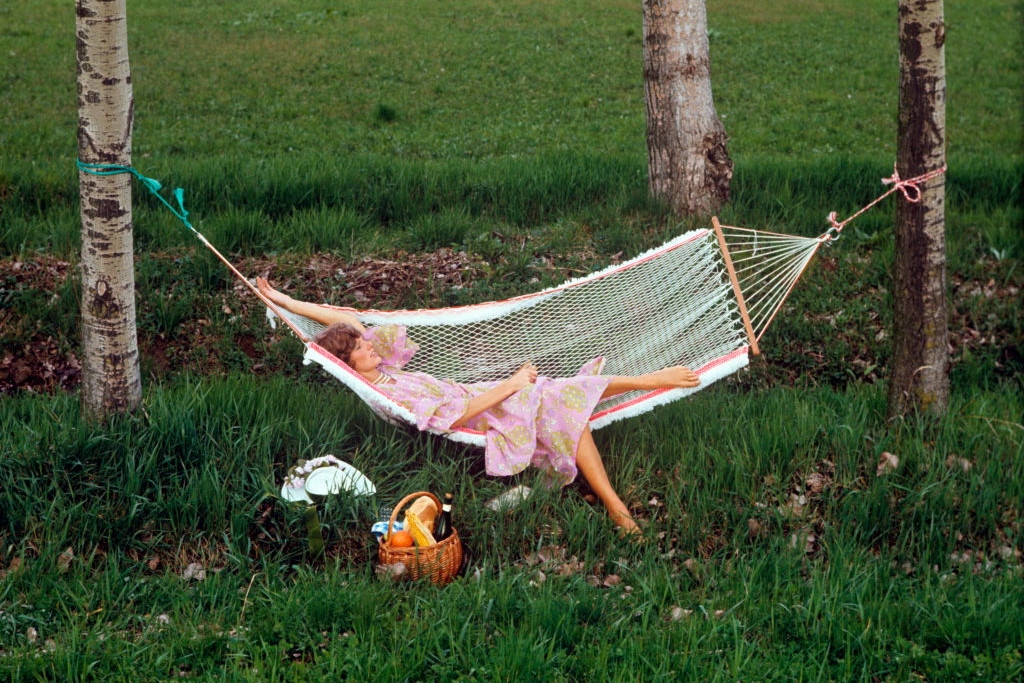 A woman relaxing on a hammock in a field