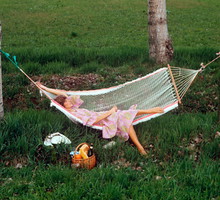 A woman relaxing on a hammock in a field