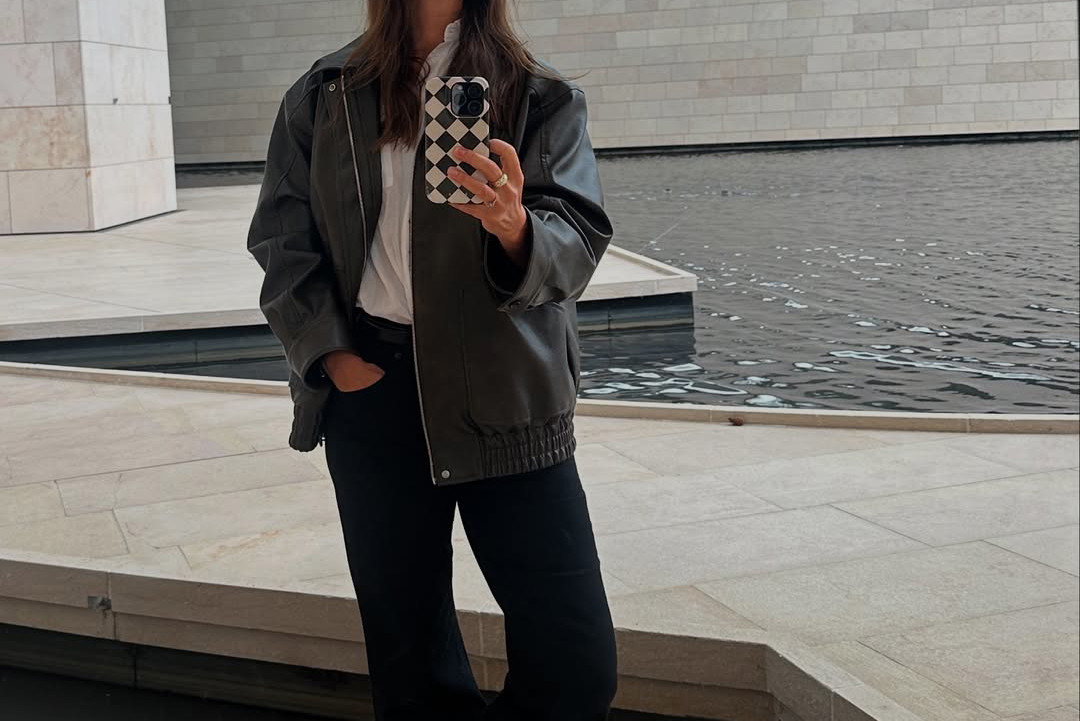 Maja Ostaszewska w czarnej kurtce "bomber jacket" i srebrnych sneakersach ASICS