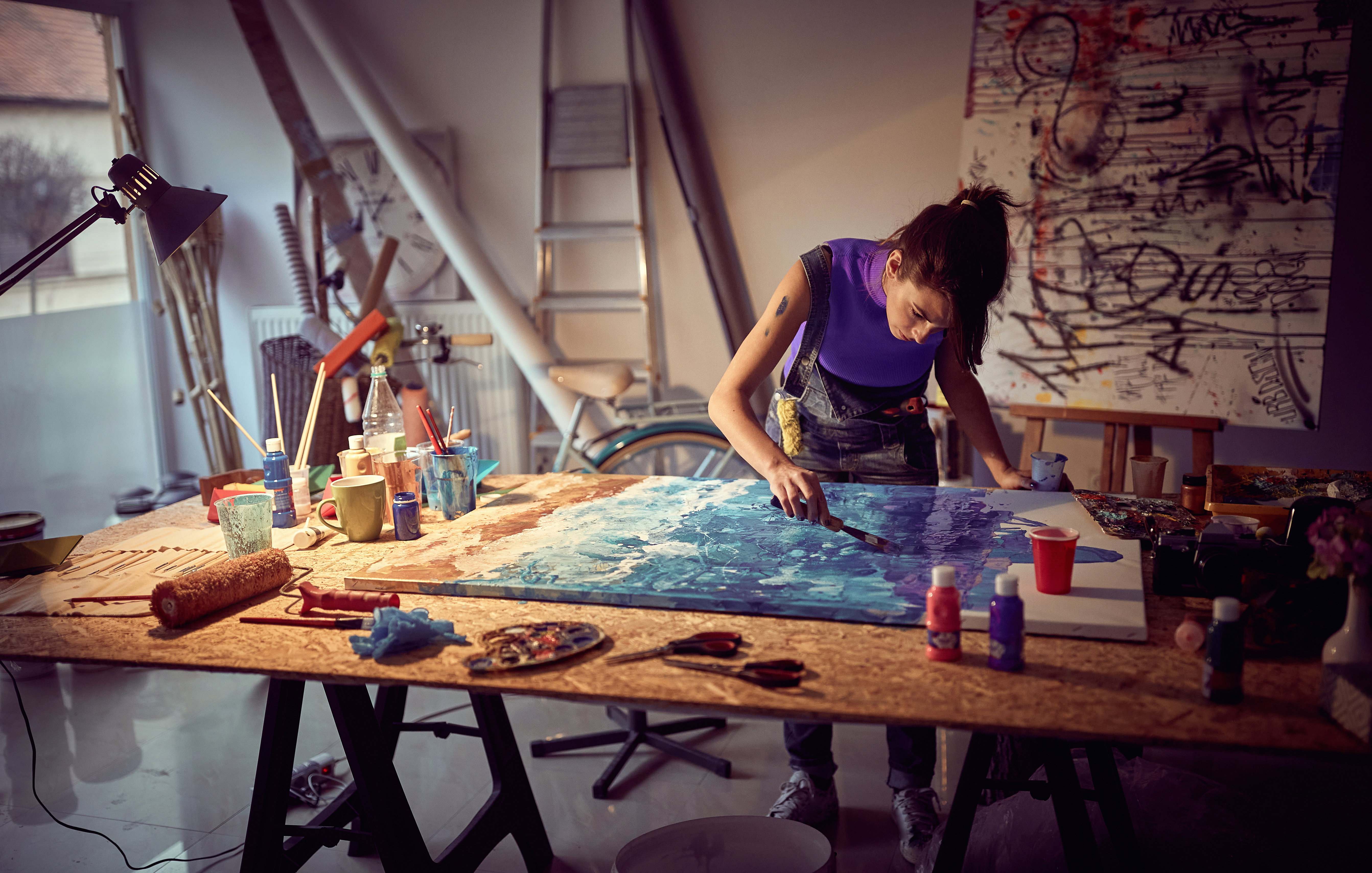 A young female artist is focused while working on a painting in