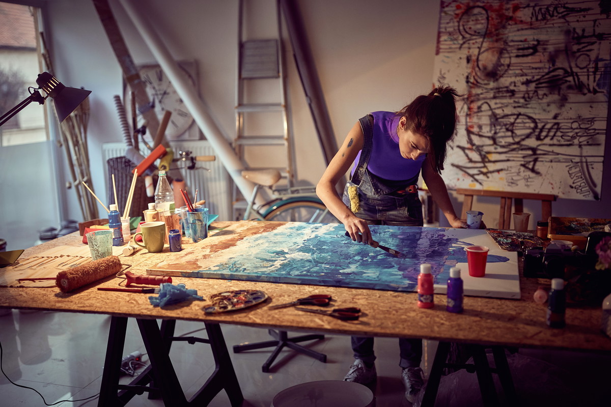 A young female artist is focused while working on a painting in