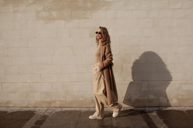 portrait of a style woman walking, enjoys a wonderful atmosphere of a vacation in fall time. The girl is wearing a urban beige sweater,