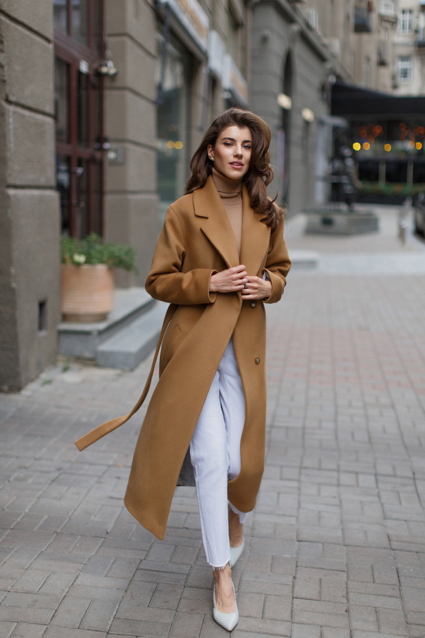 Young model with long hair in light brown coat goes towards the camera.