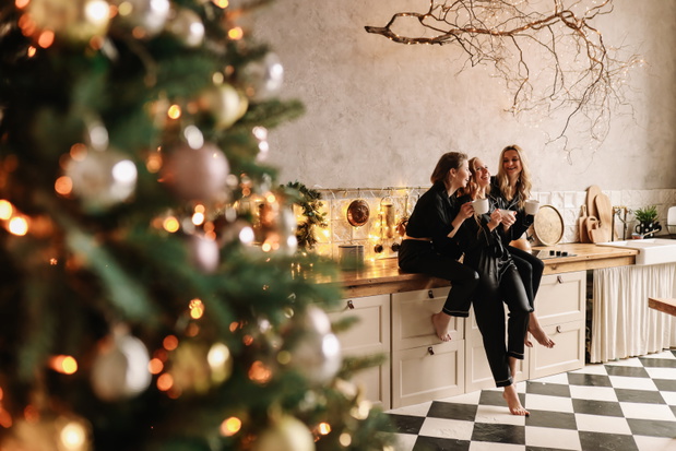 Funny girls friends in Santa hats celebrate the Christmas holiday and the new year laugh rejoice drink champagne at a party in the decorated loft style kitchen at the Christmas tree at home