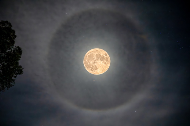 Full moon in the night sky surrounded by a Lunar Halo