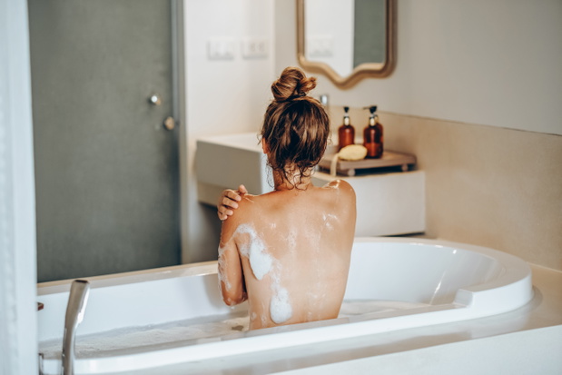 Woman using body washcloth while taking hot bath. Personal hygiene and body care