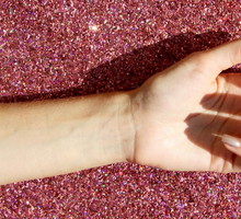 Cropped Image Of Hand Over Pink Glitter On Sunny Day