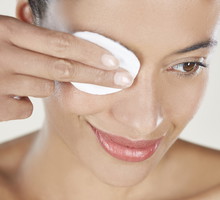 Woman removing eye make up with cotton wool pad.