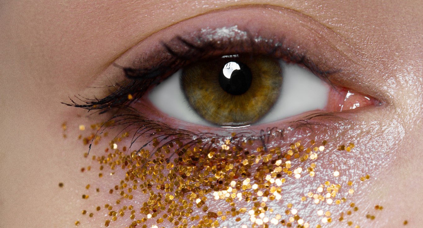 Extreme close-up of woman with golden glitters under her eye