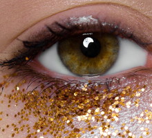 Extreme close-up of woman with golden glitters under her eye