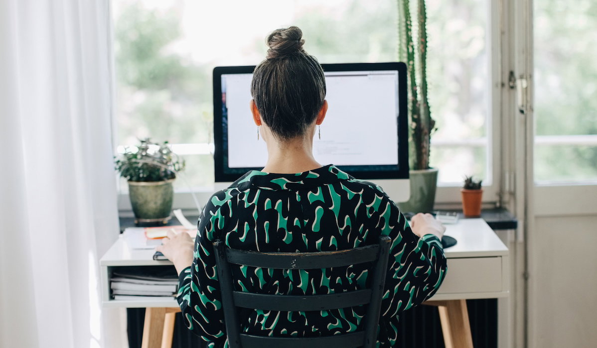 Rear view of businesswoman using computer at desk in home office