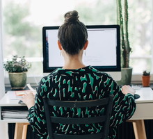 Rear view of businesswoman using computer at desk in home office