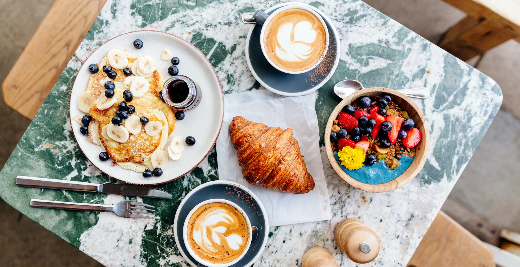 Brunch at the cafe with smoothie bowl, ricotta pancakes, croissant and cappuccino, directly above view