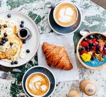 Brunch at the cafe with smoothie bowl, ricotta pancakes, croissant and cappuccino, directly above view