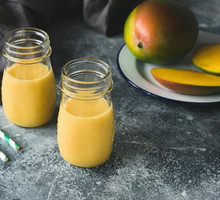 Mango smoothie in bottle on concrete background