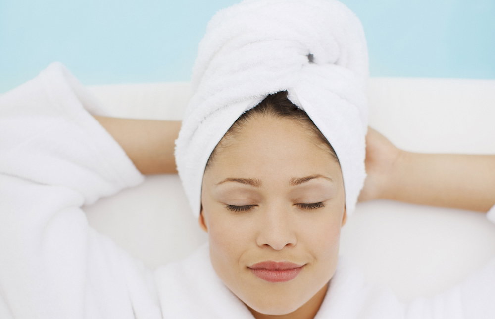 Woman with head wrapped in towel laying at poolside