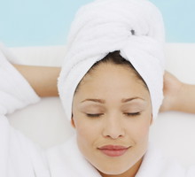 Woman with head wrapped in towel laying at poolside