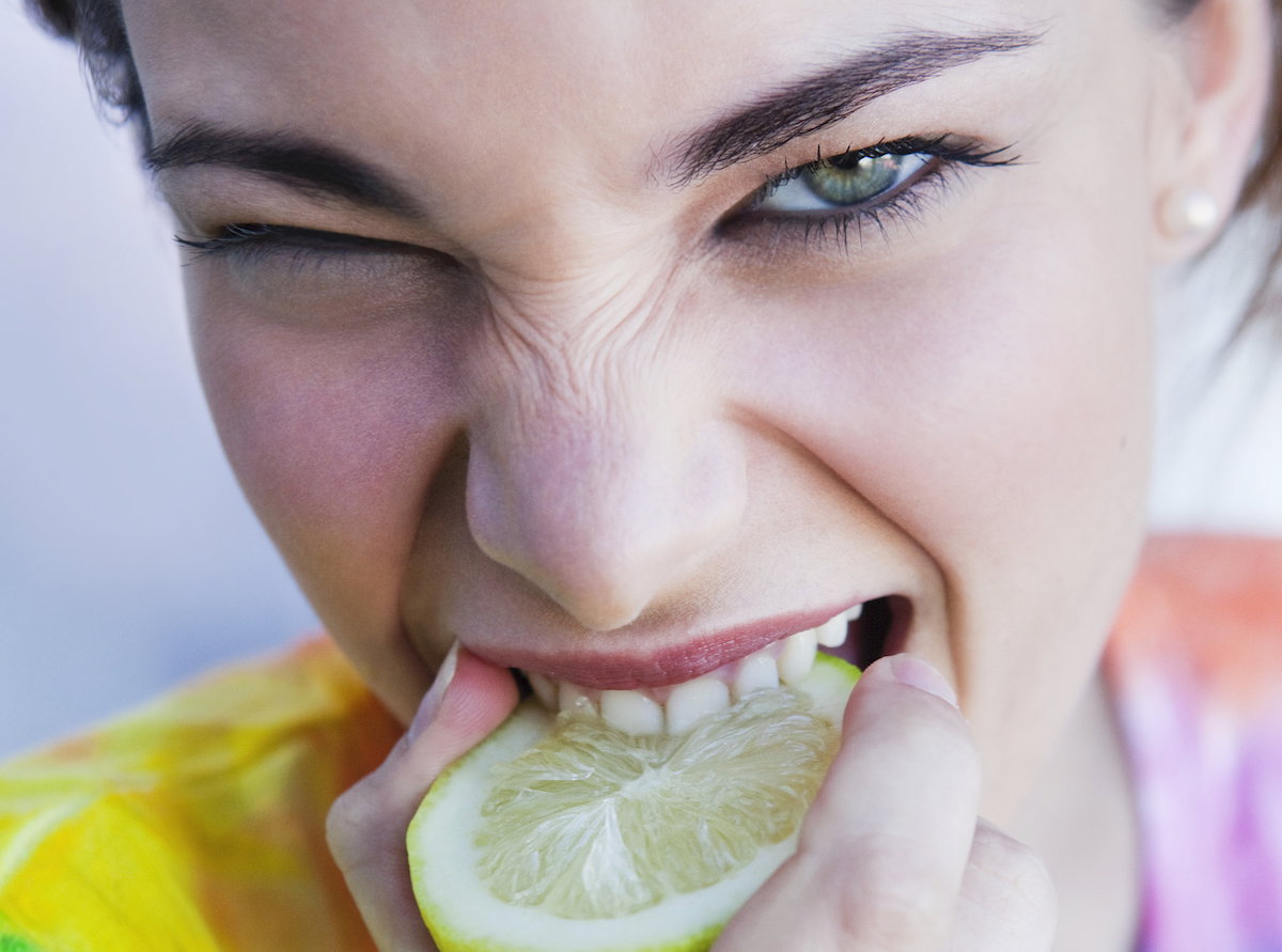 Portrait of young woman biting into lemon
