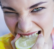 Portrait of young woman biting into lemon