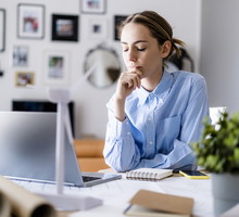Woman with closed eyes in office with wind turbine model on table