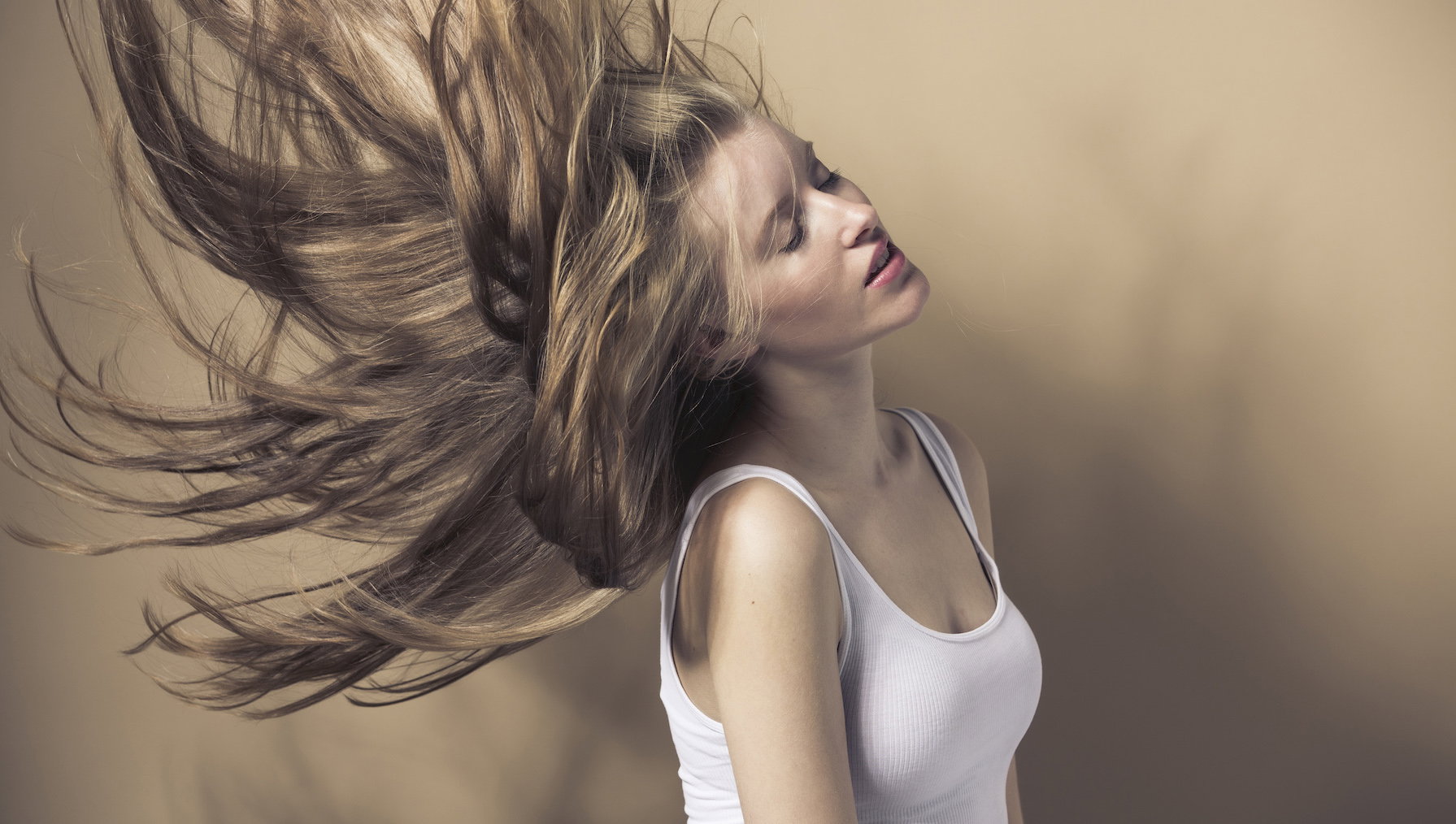 Portrait of blond young woman tossing her hair