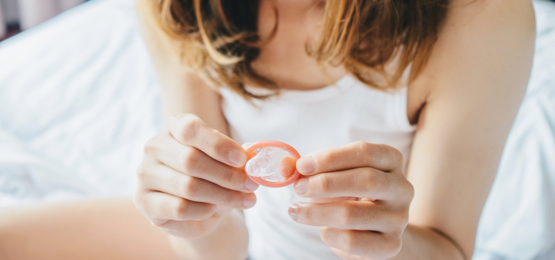 Cropped shot view of woman holding a small condom on her hand before using it with her partner.