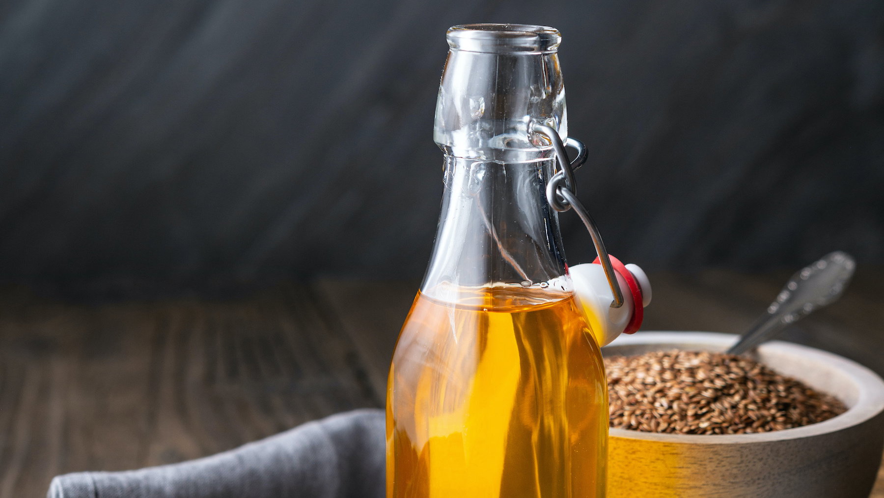 Flaxseed oil in a glass bottle, decorated with whole seeds with copy space