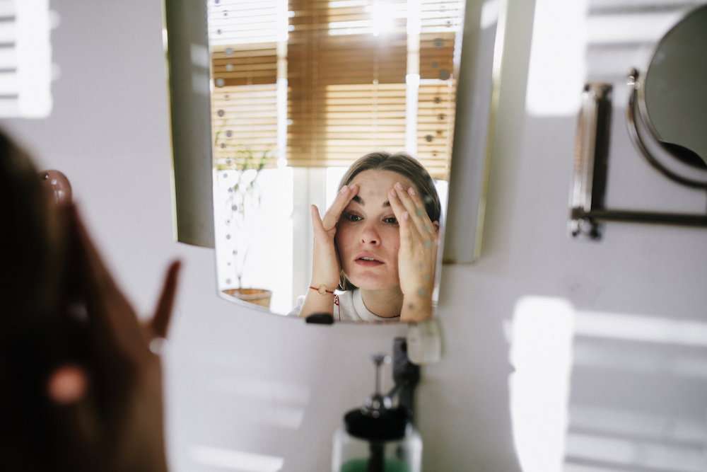 Woman looking in bathroom mirror
