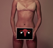 Young woman holding tablet in front of body to show womb & ovaries