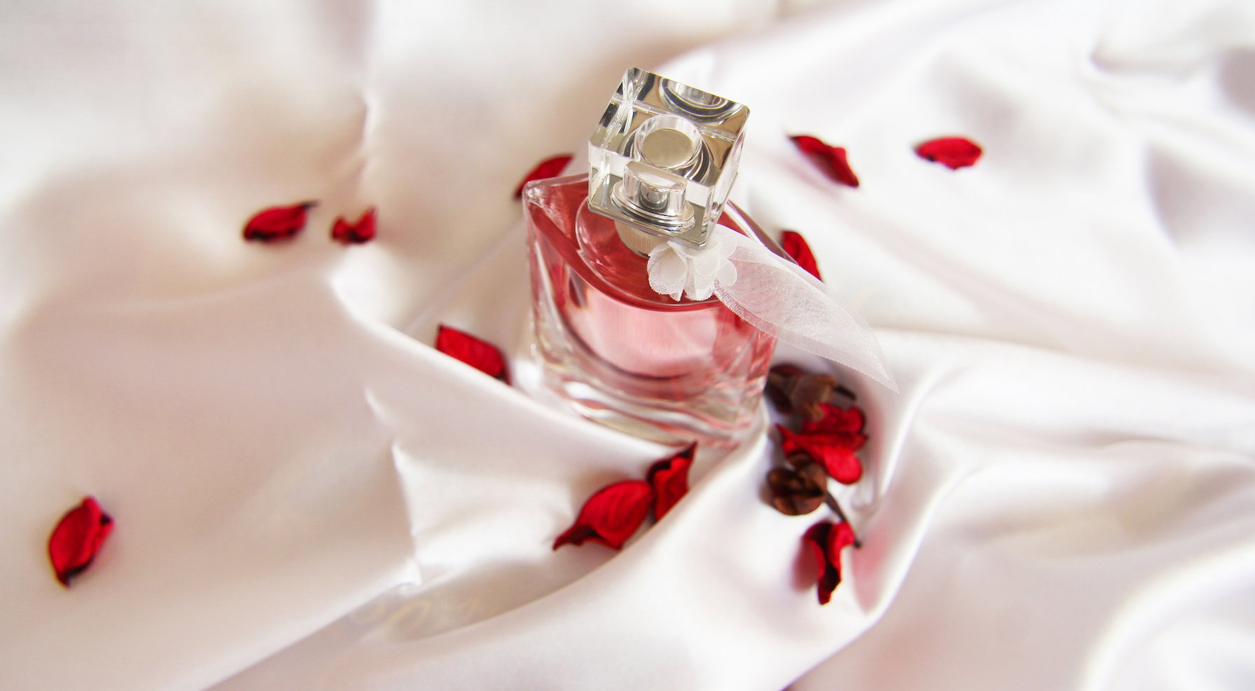 A beautiful bottle of perfume on the background of silk. Fashion &amp; Style. Rose petals.
