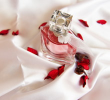 A beautiful bottle of perfume on the background of silk. Fashion & Style. Rose petals.
