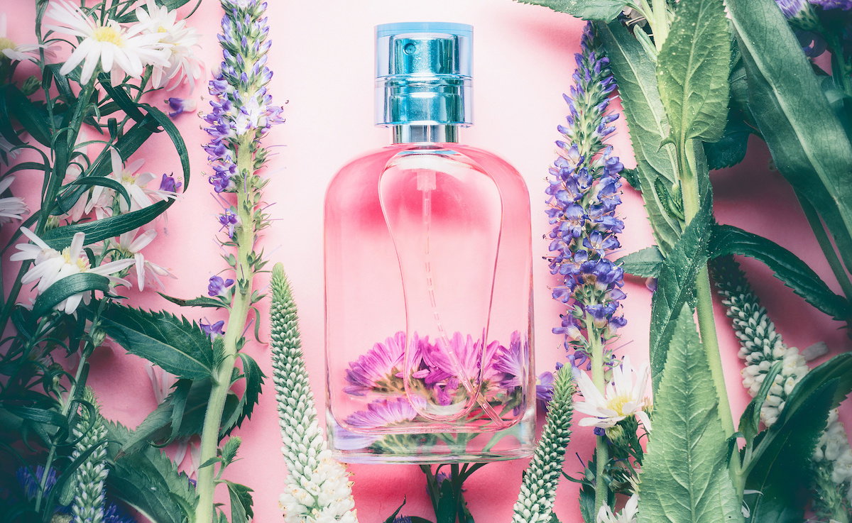 Floral Perfume bottle with plants and flowers, top view.   Perfumery, cosmetics, botanical fragrance concept.