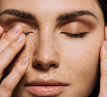 close up view of tender girl with freckles on face touching closed eyes