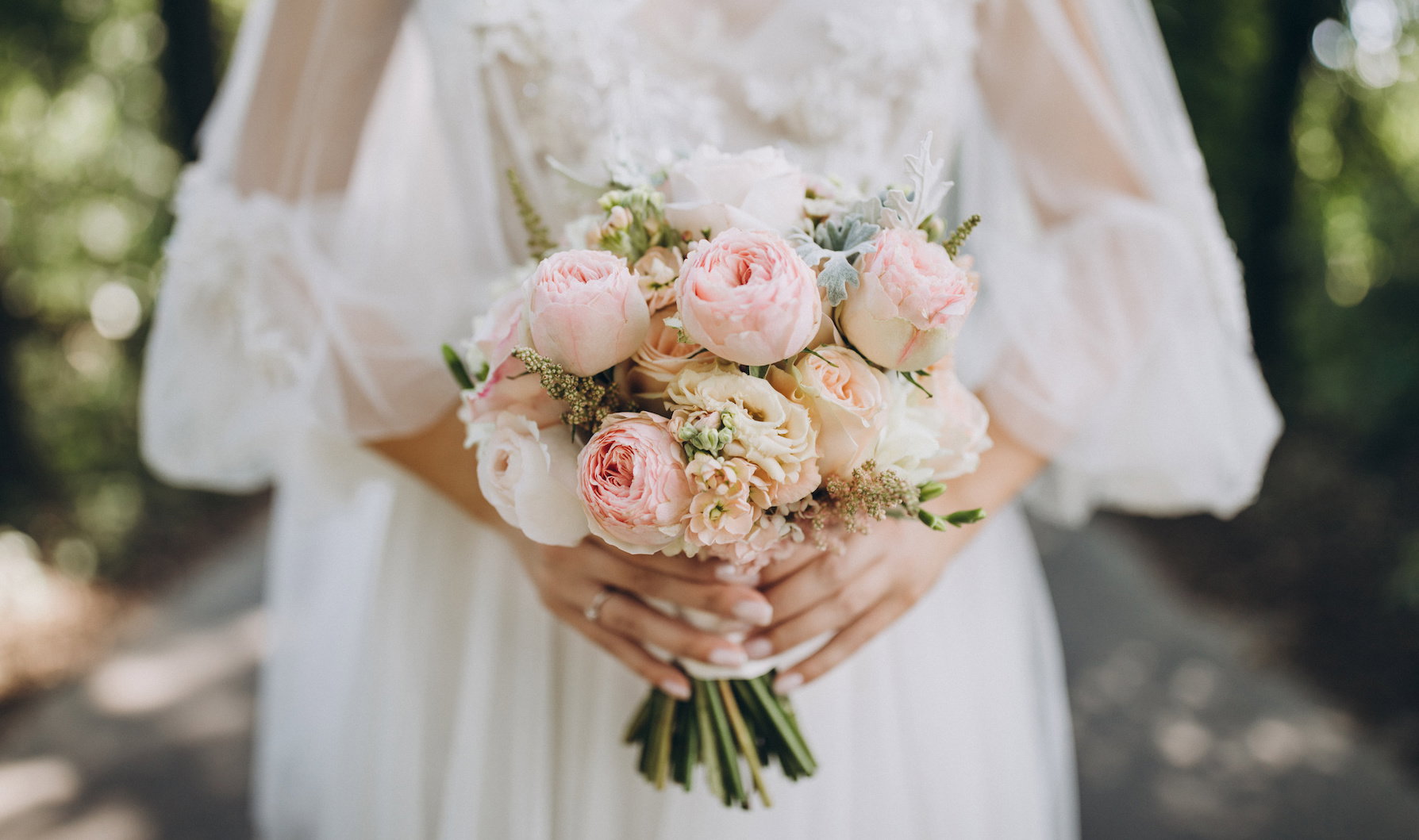 bride in a white wedding dress holding a bouquet of roses, peonies and greenery