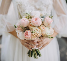 bride in a white wedding dress holding a bouquet of roses, peonies and greenery